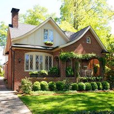 a brick house with white trim and lots of greenery on the front door is shown