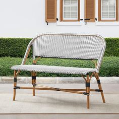 a white and black bench sitting in front of two windows with shutters on each side