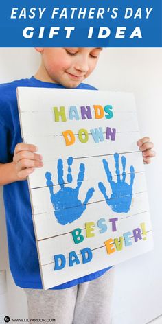 a young boy holding up a handprinted sign with the words, easy father's day gift idea