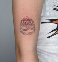 a woman's arm with a small cake tattoo on the left side of her right arm