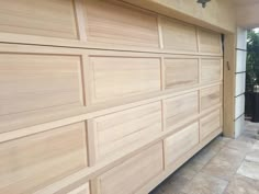 a large wooden garage door on the side of a house with tile flooring and walls