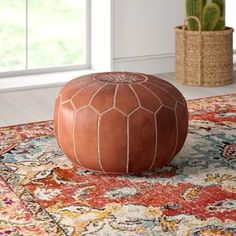 a brown leather ottoman sitting on top of a rug next to a potted plant