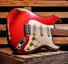 an old red guitar sitting on top of a wooden crate