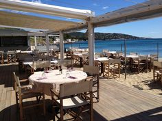 an outdoor dining area with tables and chairs overlooking the ocean