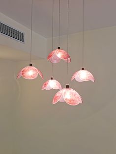 five pink lights hanging from the ceiling in a room with white walls and flooring