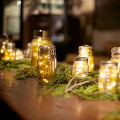 some jars with lights in them sitting on the ground next to moss and twigs,