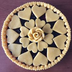 a pie with hearts and a flower on it sitting on top of a wooden table