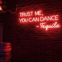 a neon sign that says trust me, you can dance tequila on the side of a brick wall