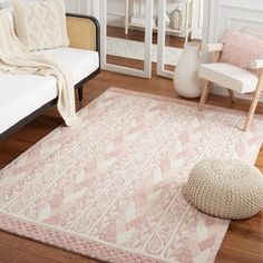 a living room area with a white couch and pink rug on the floor next to a chair