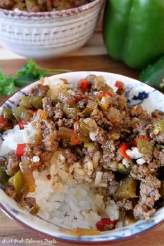 a close up of a bowl of food with rice and peppers on the table next to some green peppers