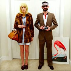 a man and woman standing next to each other in front of a wall with flamingos on it