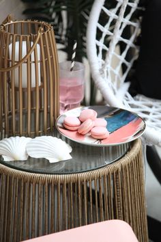 pink and white macaroons on a plate next to a wicker chair