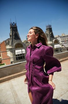 a woman in a purple dress standing on a roof