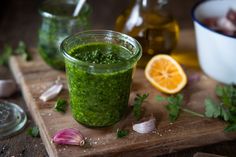 a green smoothie is sitting on a cutting board next to garlic and orange slices