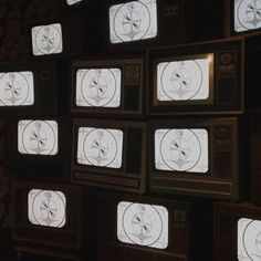 old televisions are arranged in rows and placed on the wall, all showing different times