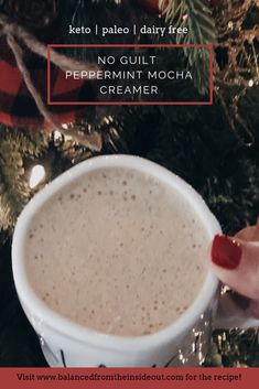 a hand holding a cup of coffee in front of a christmas tree with the words keto paleo dairy free no guilt peppermint mocha creamer