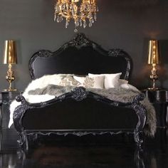 a bedroom with black furniture and chandelier above the bed, in front of a gray wall