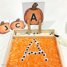 an orange tray filled with pumpkins and eyeballs next to a cut out letter