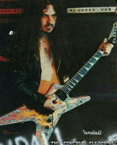 a man with long hair holding a guitar in front of an advertisement for iron maiden