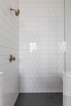 a white tiled bathroom with black and white flooring