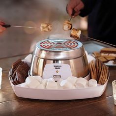 a person is cooking marshmallows in an electric crockpot on a table