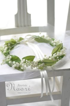 a white chair with a flower crown on it's back and ribbon around the seat