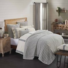 a bed in a bedroom with striped comforter and pillows