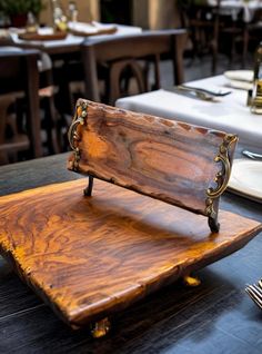 a wooden bench sitting on top of a table next to white plates and silverware