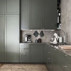 a kitchen with green cabinets and wooden floors