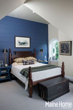 a bedroom with blue walls and white bedding, along with two tables on either side of the bed