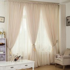 a living room filled with furniture next to a window covered in white curtains and drapes