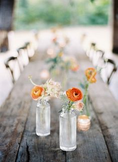 three vases filled with flowers sitting on top of a wooden table