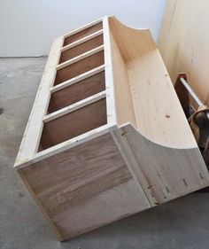 a dog is standing in front of a wooden cabinet that has drawers and wheels on it