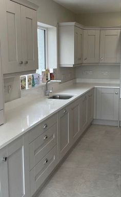 an empty kitchen with white cabinets and gray flooring is seen in this image from the front view