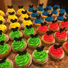 mickey mouse cupcakes with green and red frosting are on a counter top