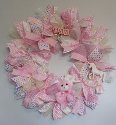 a pink and white wreath with a teddy bear