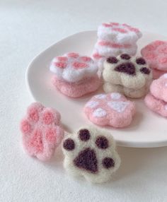 small pink and white dog paw magnets on a plate next to some smaller ones