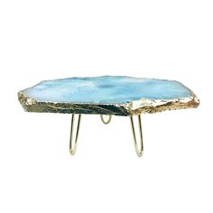 a small blue and gold table with two metal legs on it's sides, against a white background