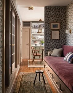 a living room filled with furniture next to a wall covered in blue and white wallpaper