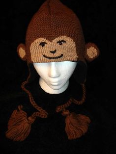 a knitted monkey hat with tassels on it's ears and eyes