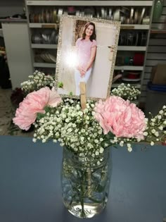 a vase filled with pink carnations and baby's breath in front of a photo