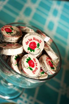 there is a glass bowl full of roses on top of the table with candy in it