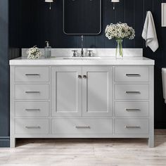 a bathroom vanity with two sinks, mirrors and flowers on the countertop in front of it