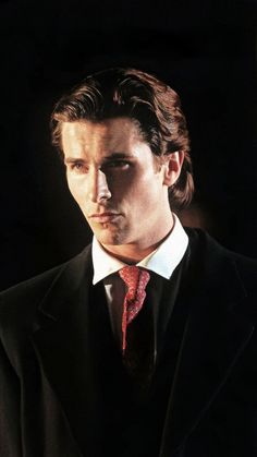 a man in a black suit and red tie