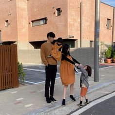 three people are standing on the sidewalk and one person is holding hands with another woman