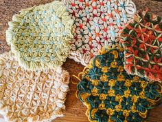 four crocheted dishcloths sitting on top of a wooden table