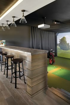 a bar with stools in front of a golf hole and green grass on the other side