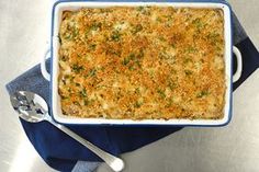 a casserole dish on a blue and white cloth with two spoons next to it