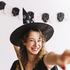 a woman wearing a witches hat and pointing at the camera with her hand out in front of her