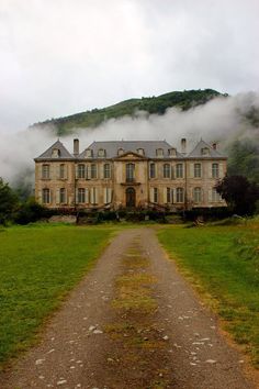 an old house with fog coming from the mountains behind it